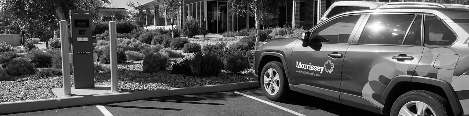 Ocular charging post with safety bollards beside a fleet car in a Perth business car park
