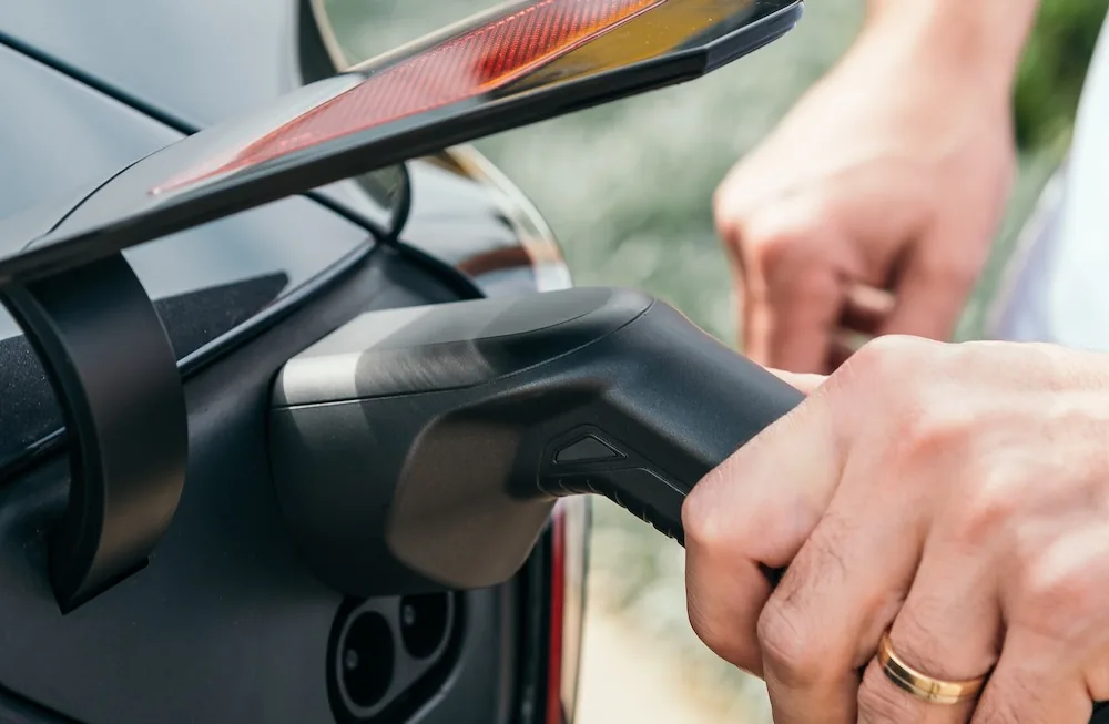 Hand plugging a charging connector into an electric car