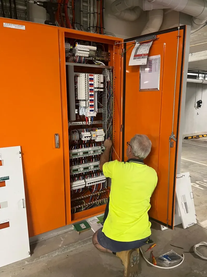 Electrician at the main switchboard planning load management for apartment EV chargers in Dalkeith