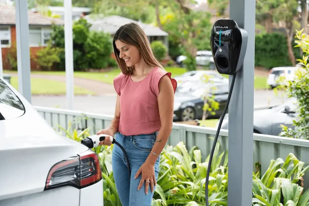Woman plugging her car into an Ocular charger mounted on a carport post